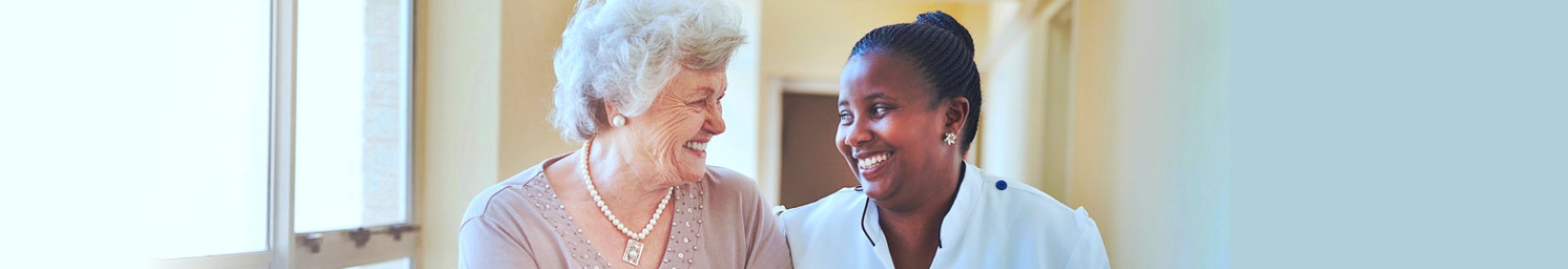 Smiling home caregiver and senior woman walking together