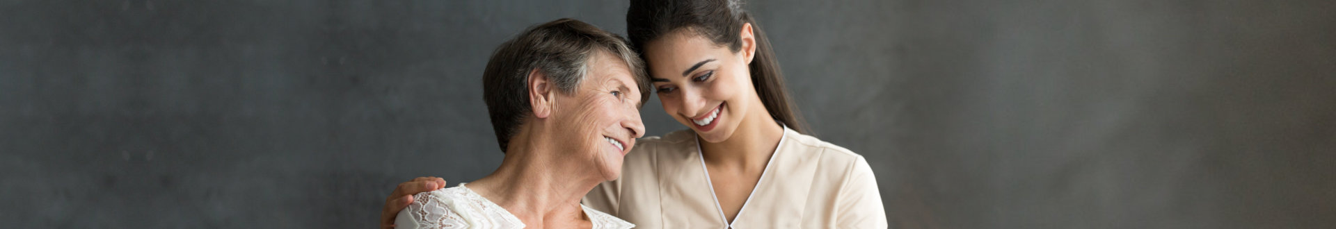 Friendly relationship between smiling caregiver in uniform and happy elderly woman